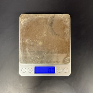 Lab Supplies Digital Balance A small silver digital laboratory balance with a worn metallic weighing platform and a blue backlit display reading zero, sitting on a black countertop. The digital balance you will use in this class may not look exactly like the one pictured here. Alternative text created using Copilot and edited by a human on February 26, 2026.